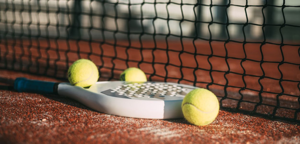 Una racchetta con palline sul campo di padel